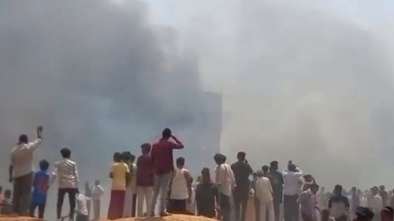 People watch smoke rising after an airplane crashed in Ahmedabad, Gujarat state, India,...