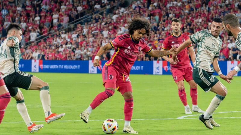 Midfielder AZ Jackson dribbles through Portland Timbers defenders.