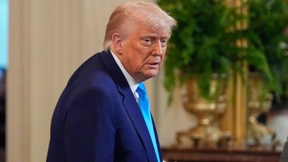 FILE - President Donald Trump holds a jersey as he departs after hosting the 2025 NCAA...