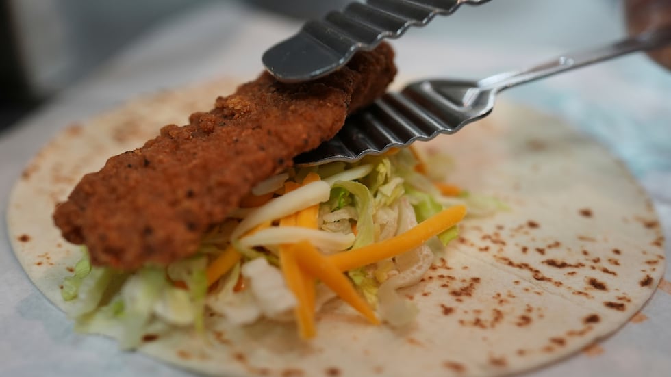 Charles L. Krumsiek, a McDonald's chef, puts a chicken on a tortilla to make a snack wrap at...