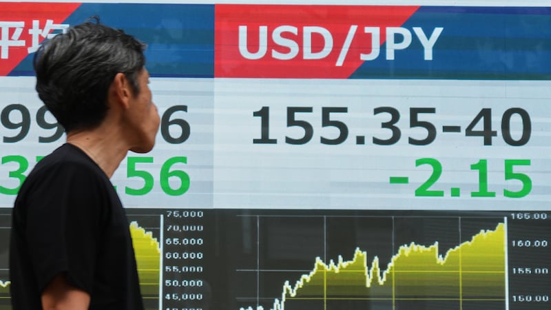 A person walks past an electronic board showing the U.S. dollar and Japanese yen exchange rate...