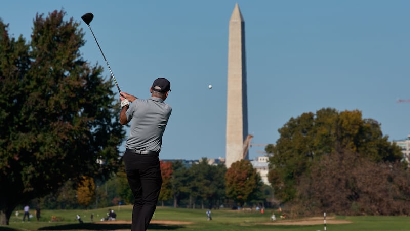 The Washington Monument is seen as a golfer takes a swing at East Potomac Park Golf Course,...